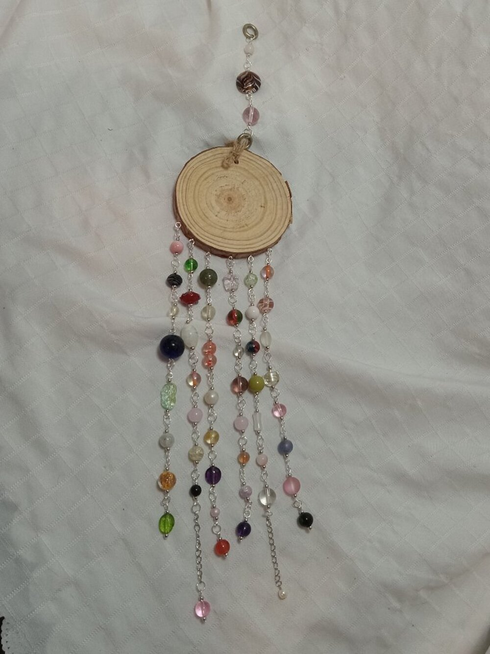 Handmade hanging decoration featuring handcrafted glass beads on a wooden base